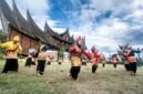 Pentas seni tradisional randai Minangkabau di lapangan dengan rumah adat beratap gonjong di belakangnya. (Foto: Dok. Wikimedia Commons/Deni Dahniel (CC BY-SA 4.0))