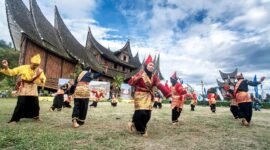 Pentas seni tradisional randai Minangkabau di lapangan dengan rumah adat beratap gonjong di belakangnya. (Foto: Dok. Wikimedia Commons/Deni Dahniel (CC BY-SA 4.0))