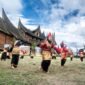 Pentas seni tradisional randai Minangkabau di lapangan dengan rumah adat beratap gonjong di belakangnya. (Foto: Dok. Wikimedia Commons/Deni Dahniel (CC BY-SA 4.0))